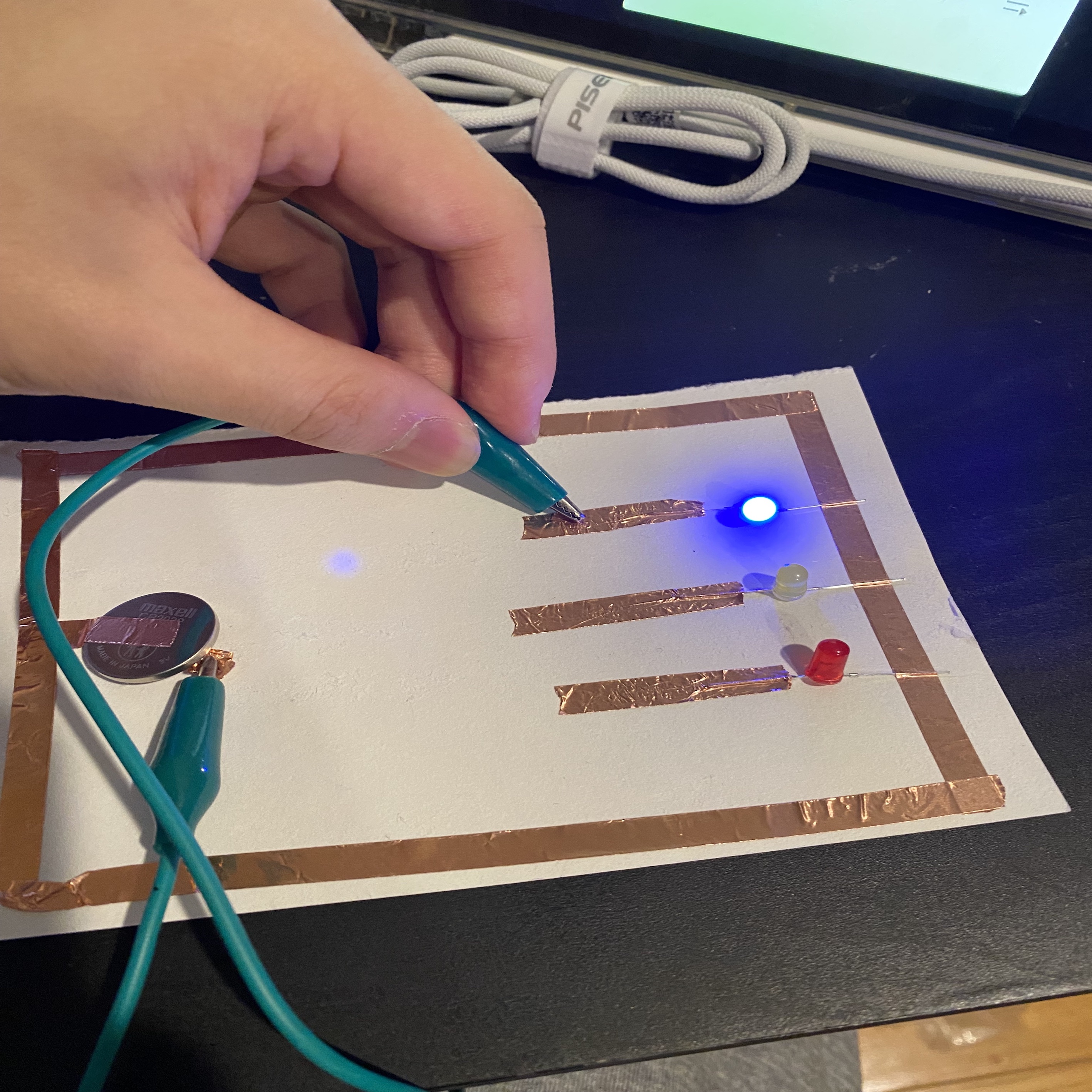 A circuit that allows the user to select one of the three LED lights to light up by touching the wires.(blue on)